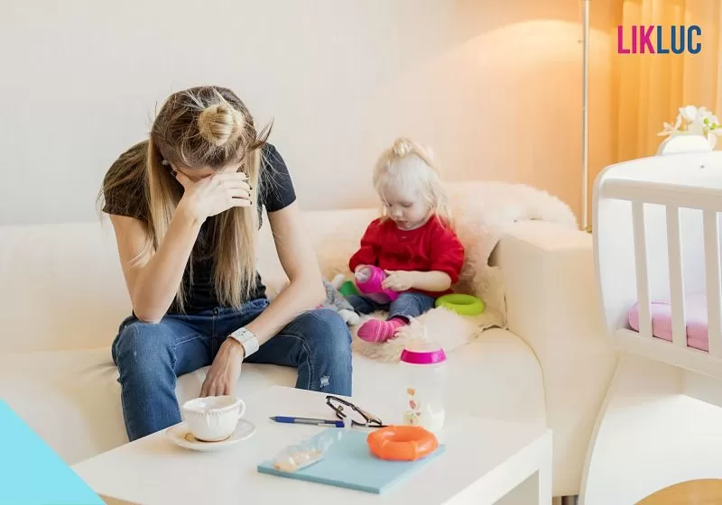 mãe com a cabeça baixa ao lado de bebê