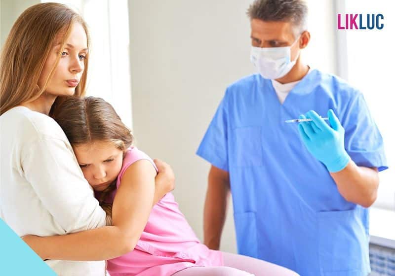 Mãe acalmando a filha que irá tomar uma injeção