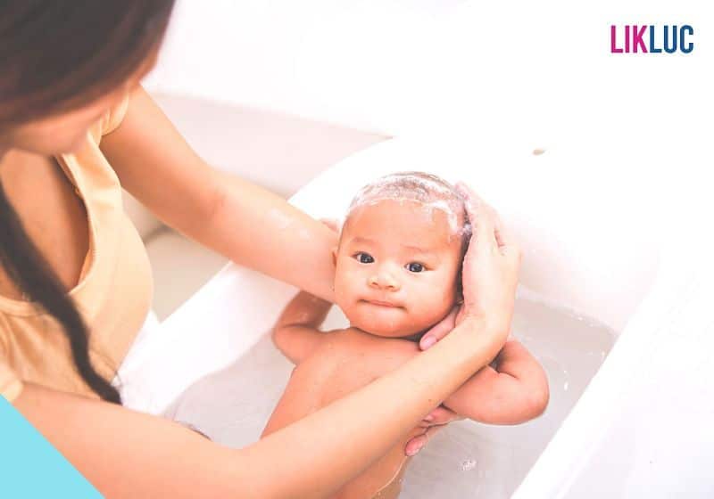 bebe tendo sua cabeca lavada pela mae no banho