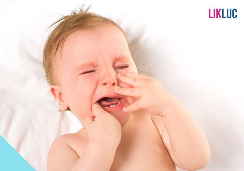 Bebê chorando com mão na boca