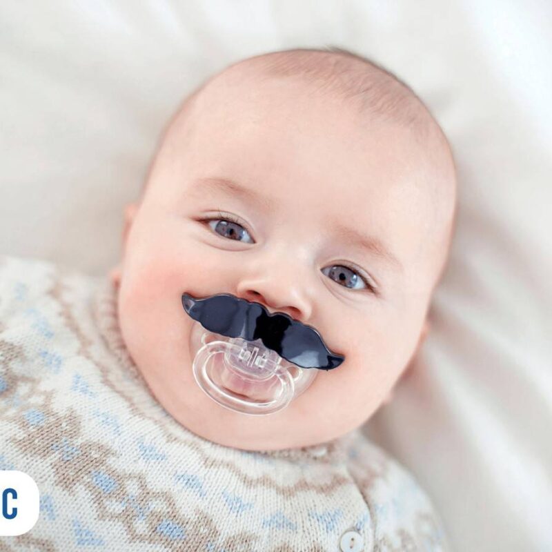 Bebê deitado e com chupeta com formato de bigode