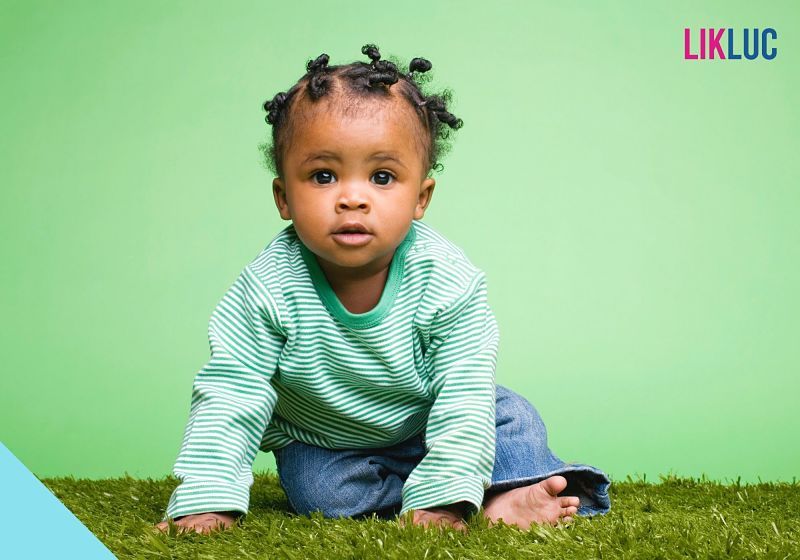 bebê sentada na grama com fundo verde