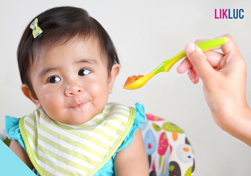 Bebê sorrindo enquanto come comida na colher