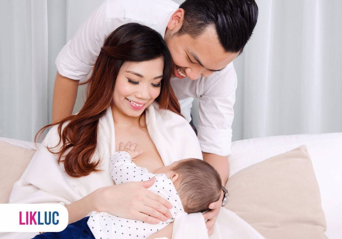 mãe amamentando bebê com pai ao lado acompanhando