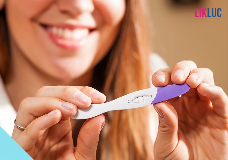 mulher segurando teste de gravidez roxo sorrindo