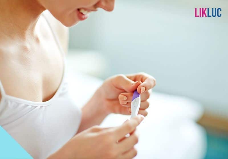 mulher sorrindo segurando teste de gravidez de fármacia