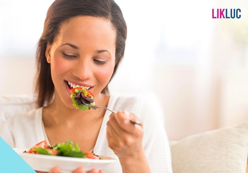 mulher comendo salada enquanto sorri mulher comendo salada enquanto sorri