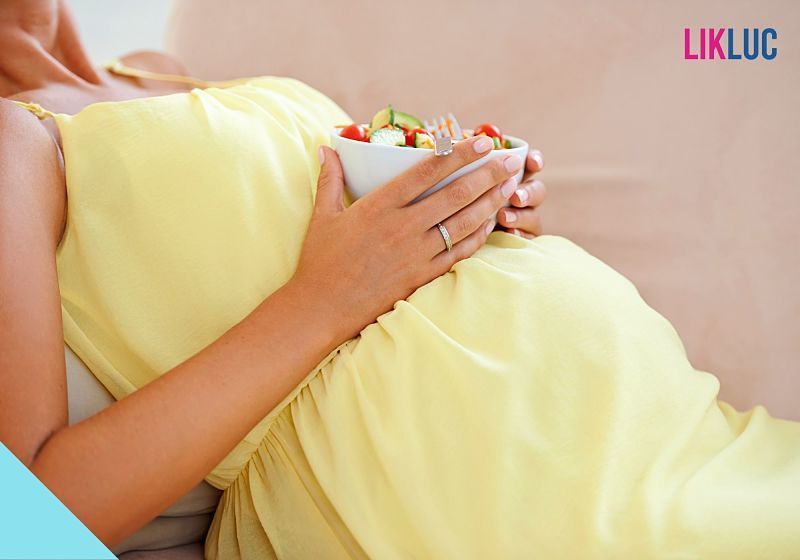 Gestante levemente sentada segurando bowl com verduras
