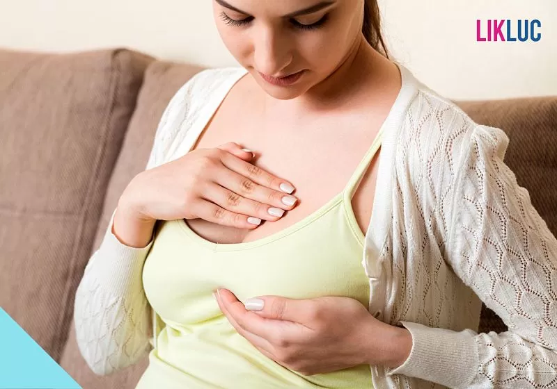 mulher sentada apertando o seio