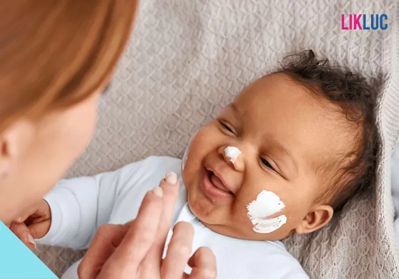 pomada antiassadura mae brincando com bebe deitaod na cama passando pomada nas bochechas dele