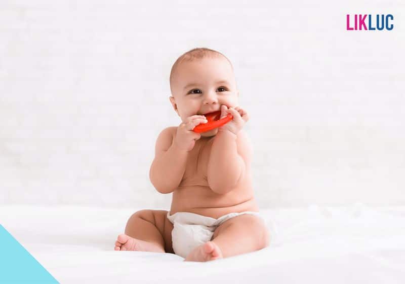 mordedor infantil bebe sentado segurando mordedor laranja