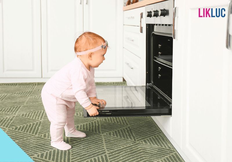 bebe na cozinha inspecionando forno com tampa aberta