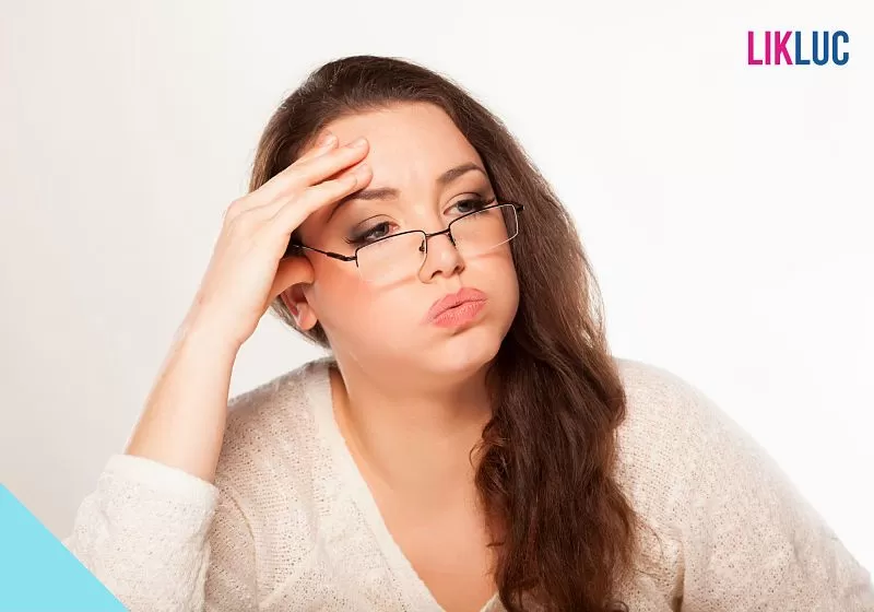 mulher com a mao na cabeça fazendo expressao de cansaço