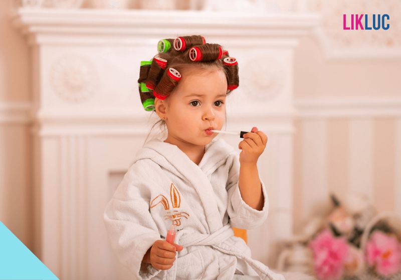 crian%C3%A7as brincando com gloss %281%29 Imagem de um criança com bobs no cabelo, roupão e passando batão na boca