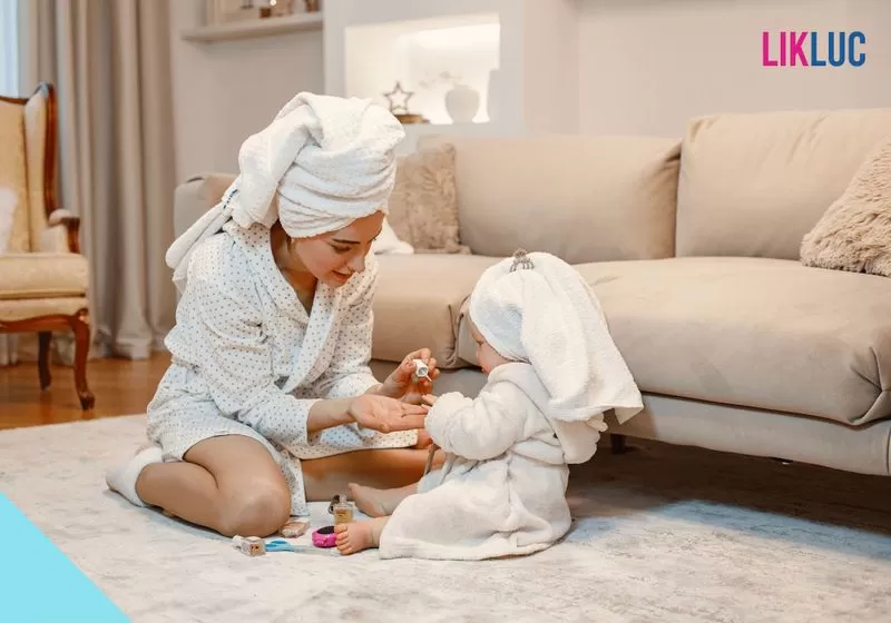 m%C3%A3e brincando com beb%C3%AA %281%29 Mãe e sua filha com roupão sentadas no chão após tomar banho