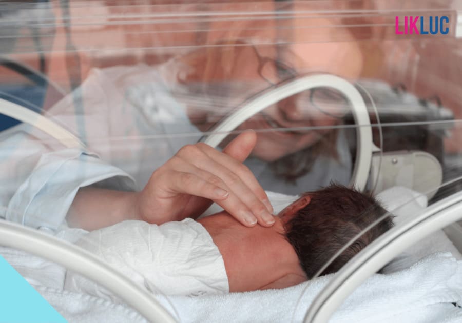 bebe deitado na incubadora de barriga pra baixo e mulher acariciando suas costas levemente