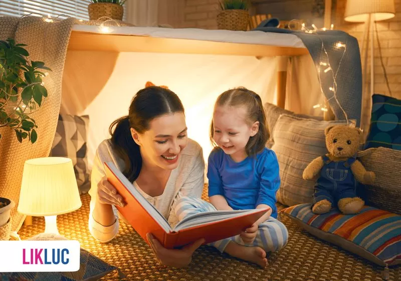 mae e filha em cabaninha juntas lendo um livro e sorrindo