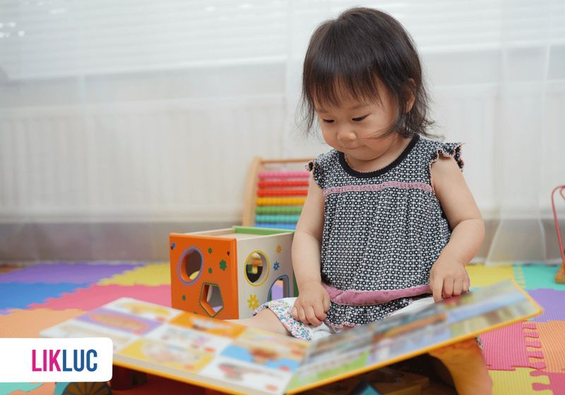 Desde qual idade incentivar meu filho a ler menininha em brinquedoteca sentada no chao com livro