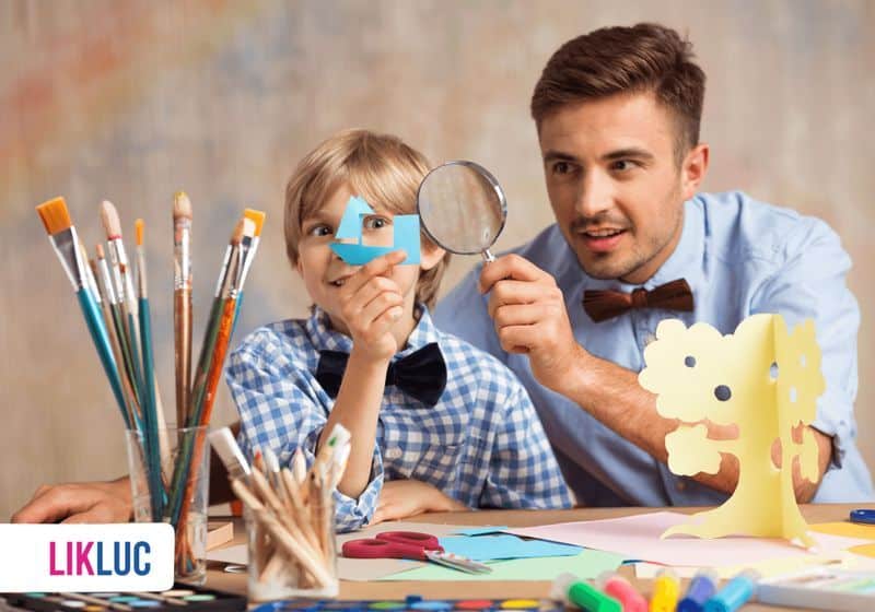 A importancia do estímulo a criatividade pai e filho brincando junto de recortes em mesa com varios materiais
