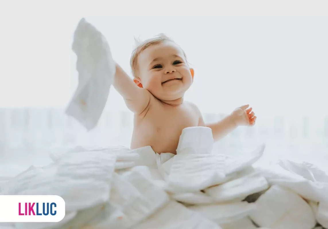 Bebê sentado e segurando uma fralda na mão