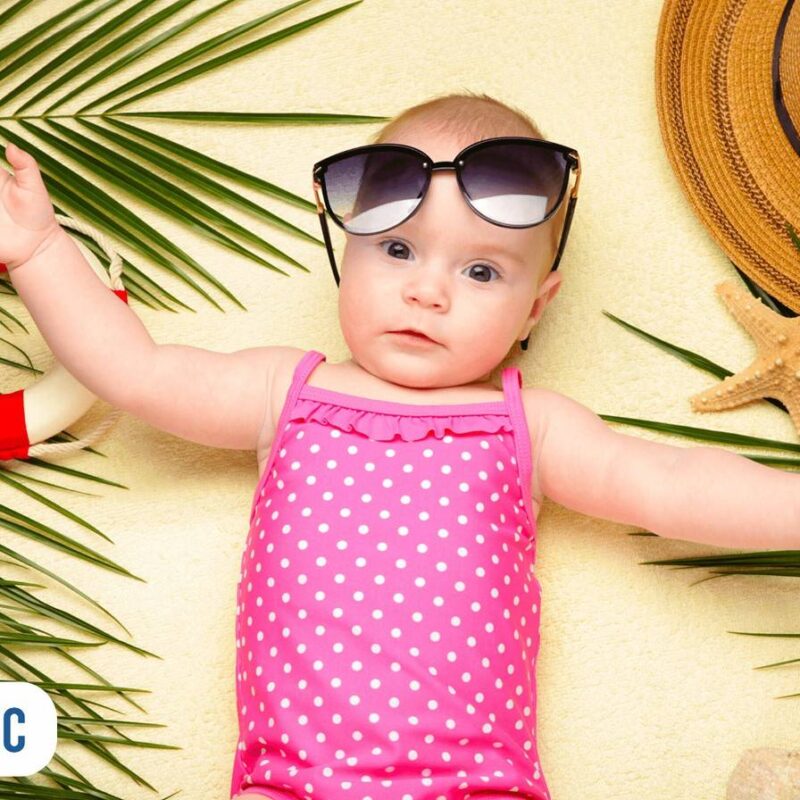 bebê de 1 mês na praia com maio rosa e um óculos de sol