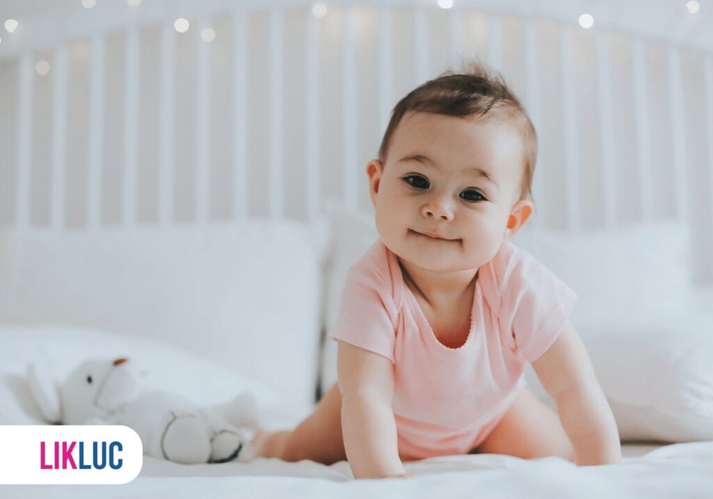 bebe engatinhando em cima de cama e olhando em direção à câmera