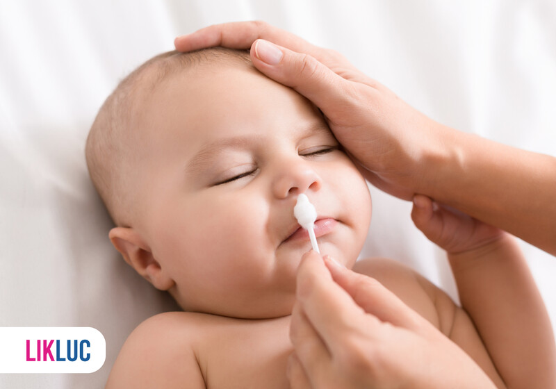 Bebê recebendo cuidados de higiene facial.