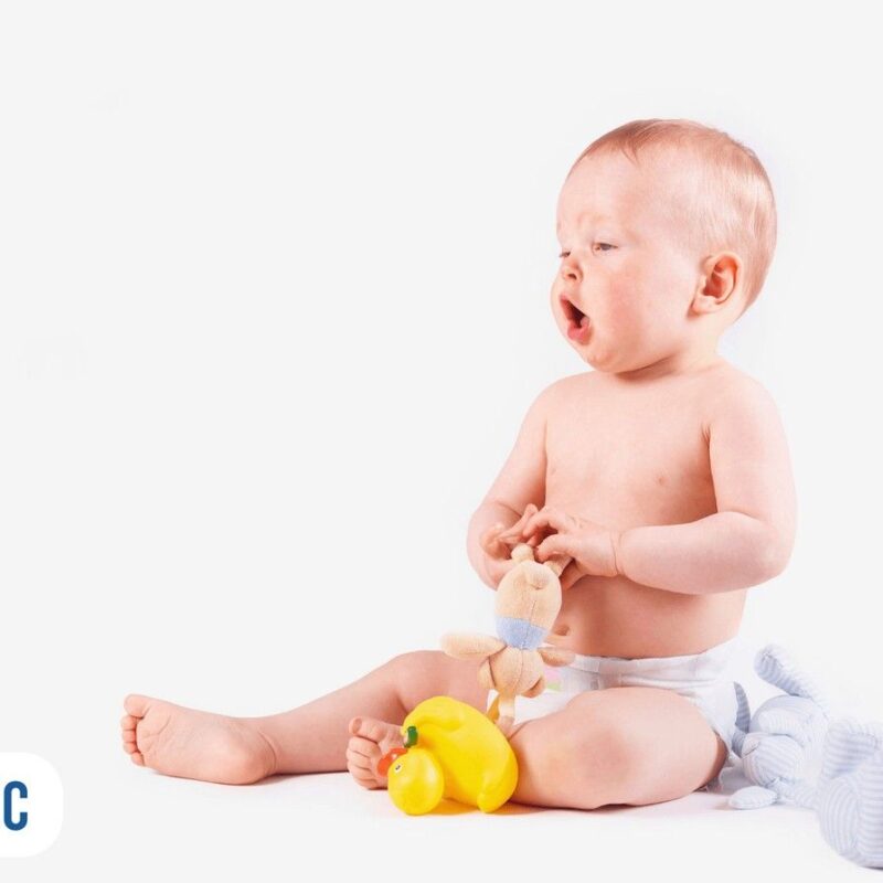 bebê senado com vários brinquedos ao seu redor