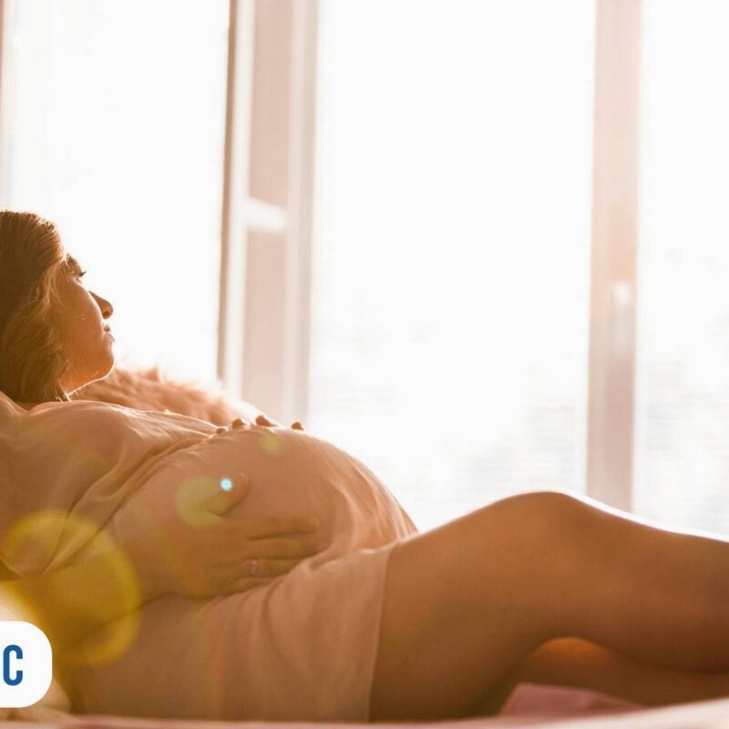 Gestante olhando pela janela e segurando a barriga