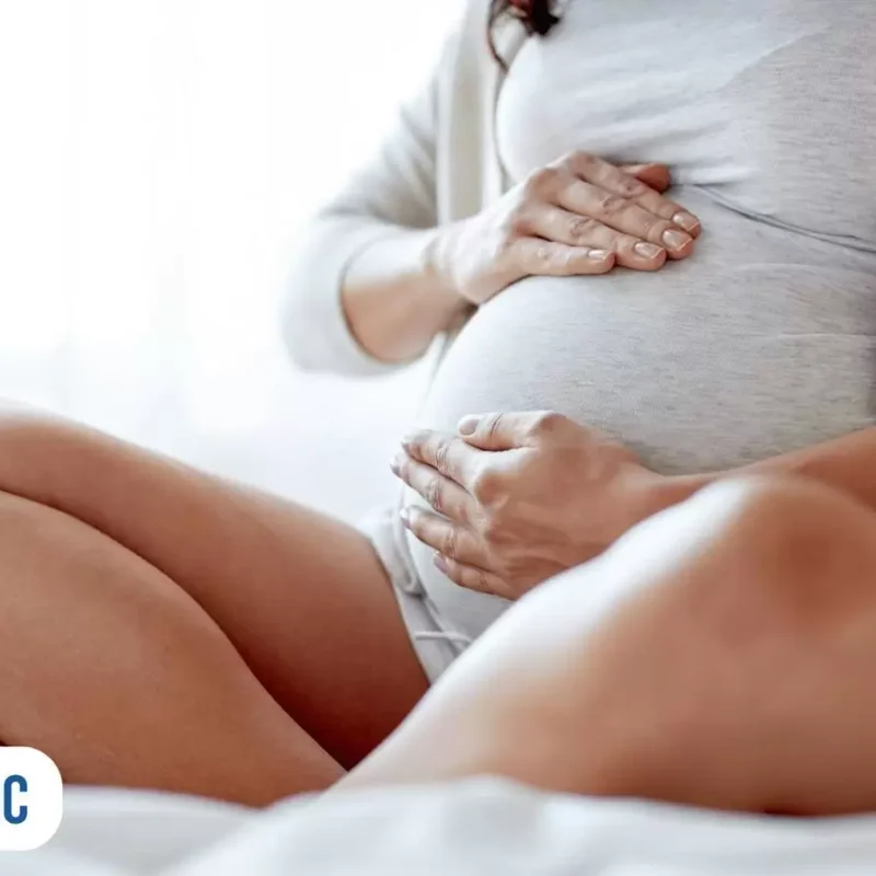 Gestante sentada com as mão sobre sua barriga
