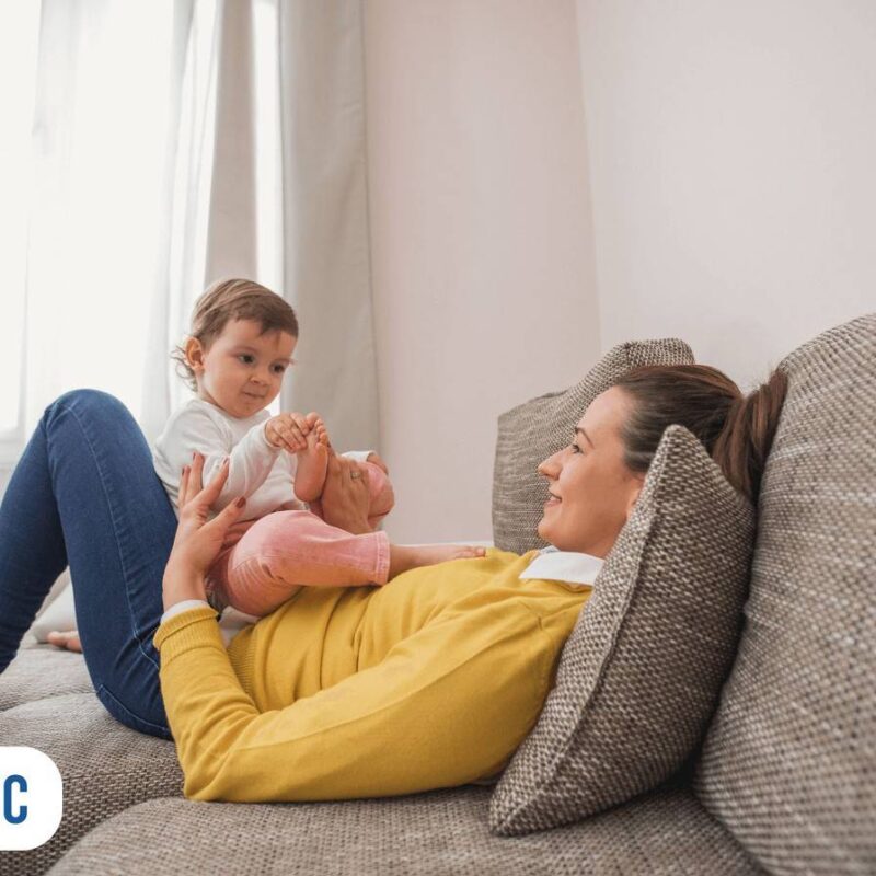 Mamãe sentada no sofá com o seu bebê no colo