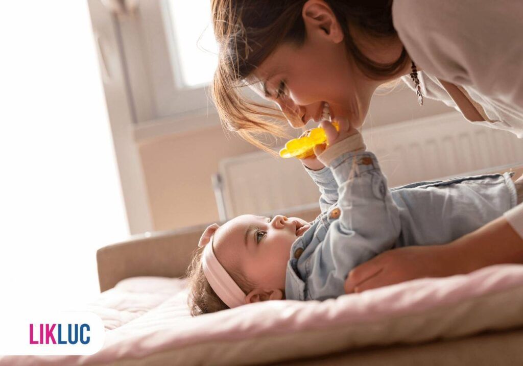 Mamãe sorrindo enquanto o seu bebê brinca com seu brinquedo