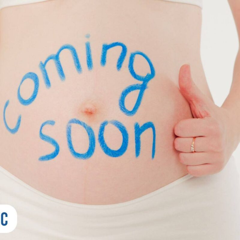 Imagem de uma gestante de 8 semanas com a frase escrita na barriga coming soon