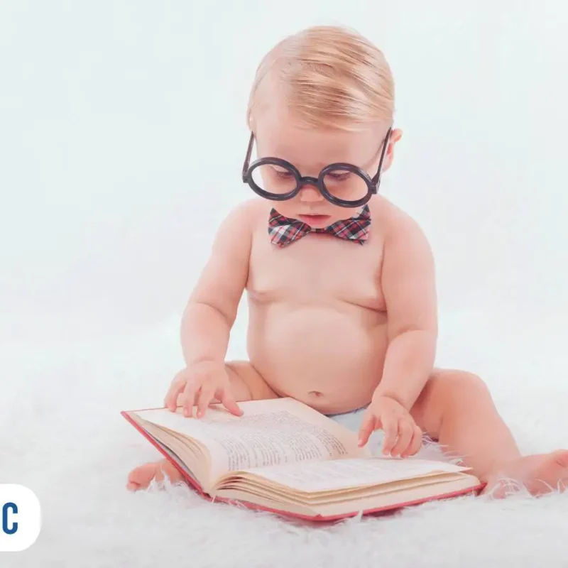 Bebê de óculos e gravata lendo um livro