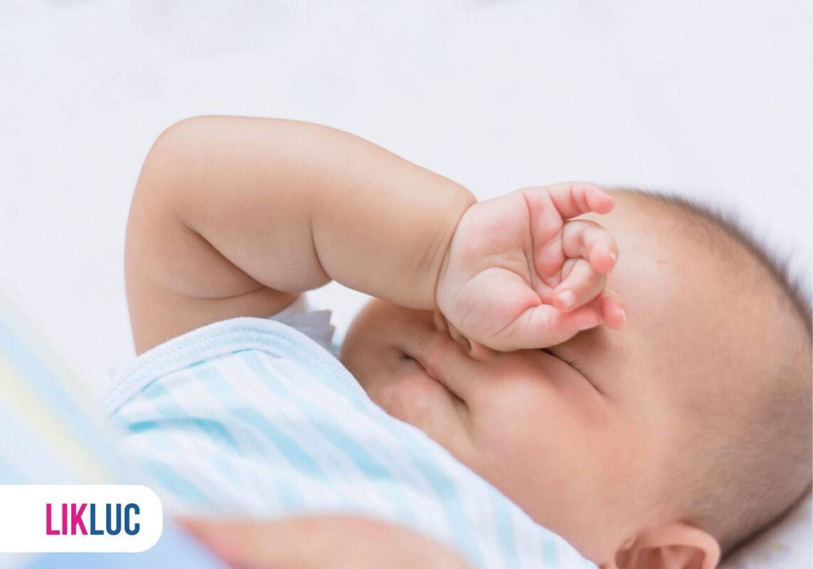 bebe deitado coçando o próprio olho com a mãozinha