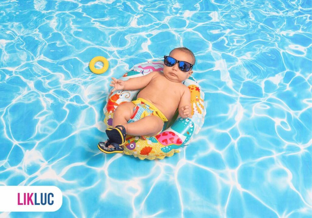 Bebê de óculos escuro deitado numa boia em uma piscina