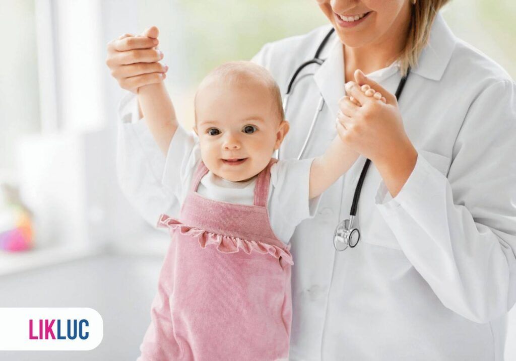 bebe sorrindo com as mãozinhas para cima, sendo segurada por sua pediatra