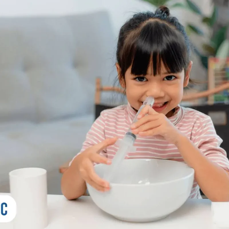 Menina utilizando uma seringa para fazer uma lavagem nasal