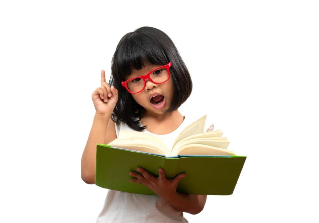 Criança usando óculos vermelho e segurando livro de capa verde