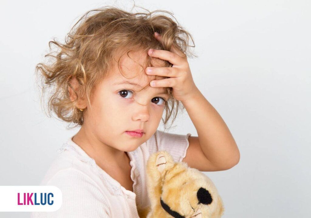 criança com mão na cabeça e segurando ursinho de pelúcia