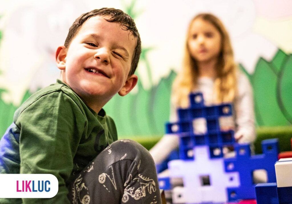 Criança piscando e outra no fundo observando ocm brinquedo em mãos