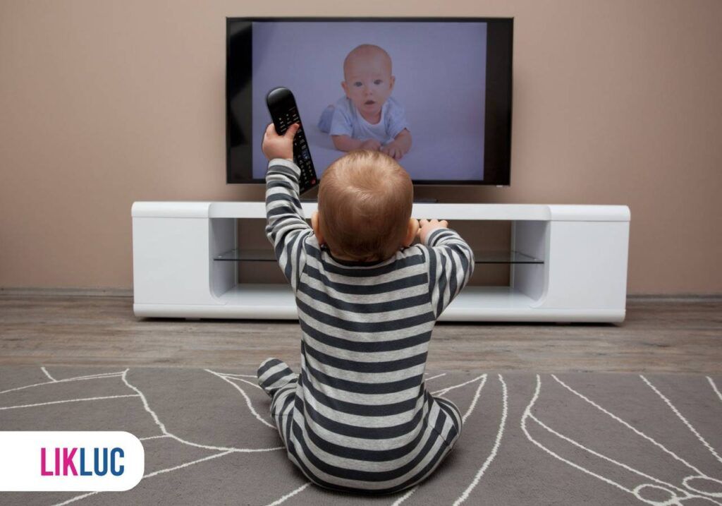 Criança em frente a TV e segurando controle remoto sentada ao chão