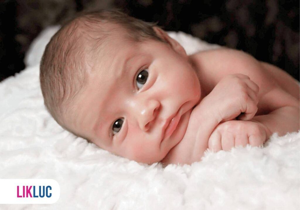 Recém nascido deitado de olhos abertos e braços cruzados