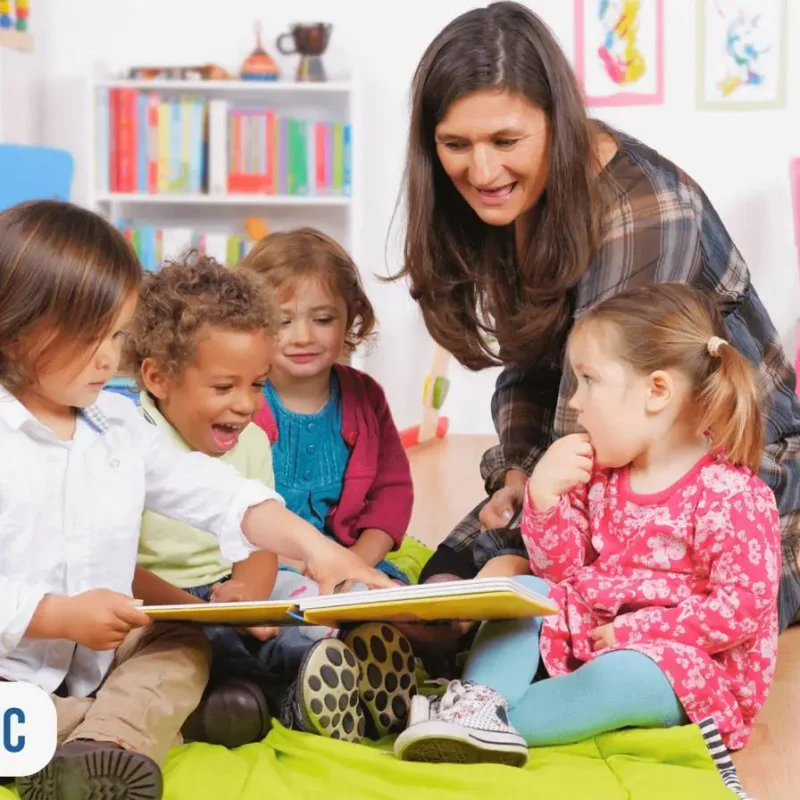 Professora orientando crianças em creche, sendo uma delas segurando livro aberto