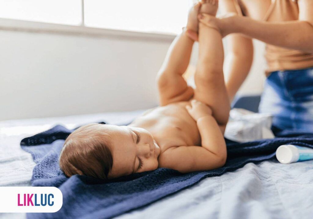 mãe trocando fralda de bebê que está deitado