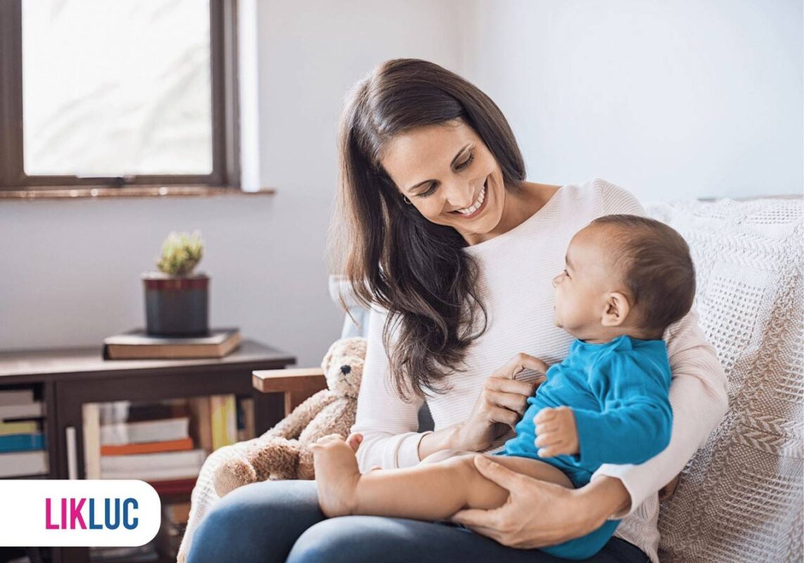 Mãe segurando bebê no colo e sentada no sofá
