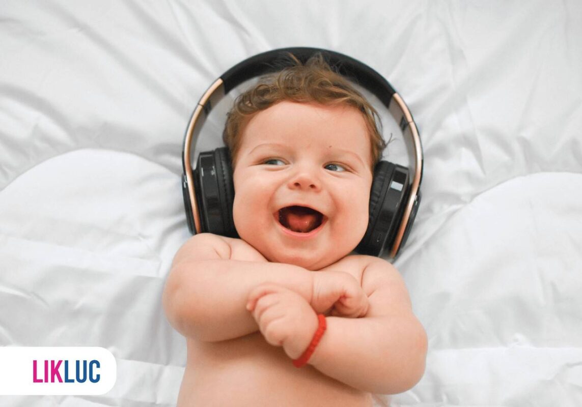 Bebê deitado com fone de ouvido, escutando música e sorrindo