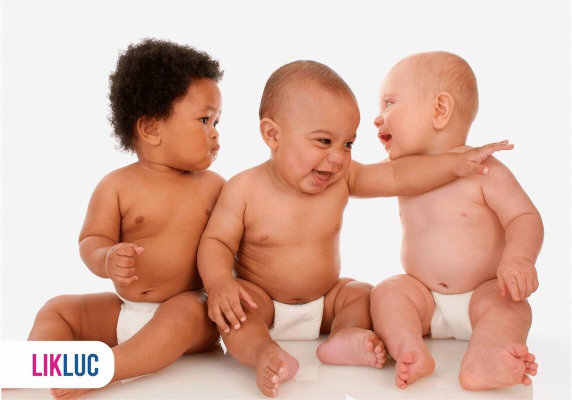 Três bebês sentados no chão e todos sorrindo