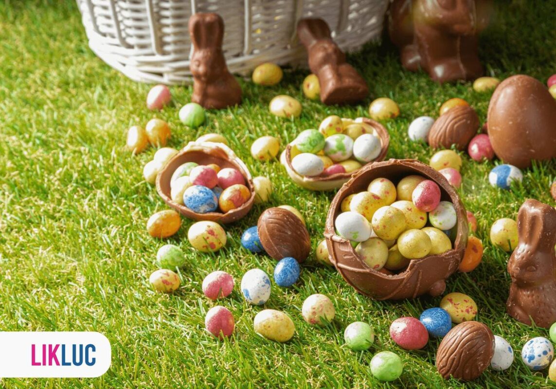 Chocolate em formato de ovos e de coelhos na grama, com cestas e vários outros ovos coloridos