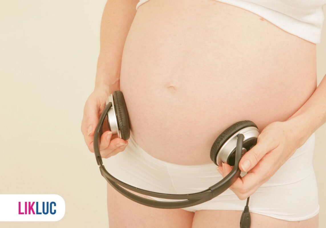 Mãe grávida segurando fones de ouvido apontados na barriga